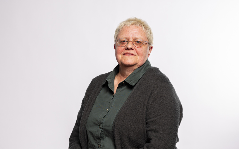 sitzende Frau mit kurzen grauen Haaren und Brille