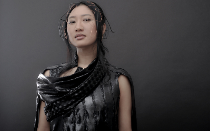 An Asian read young woman in front of a gray background