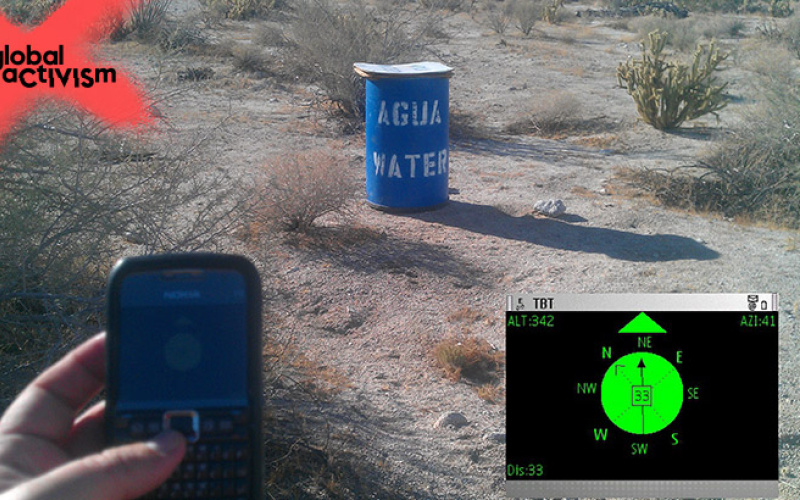 A Hand holding a mobile phone and a barrel in the field