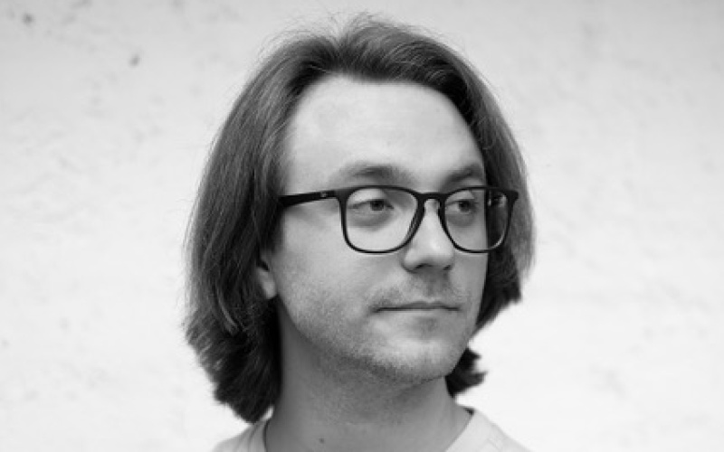 Young man with glasses looking over his left shoulder.