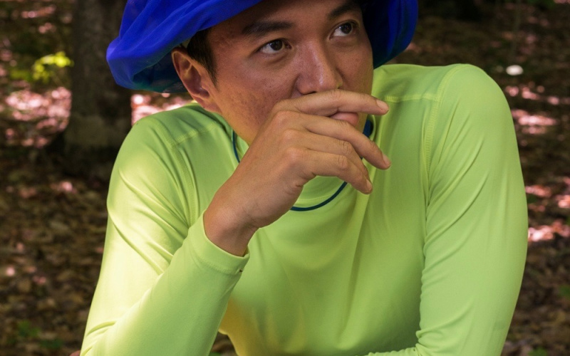 A man in a long green shirt and a blue turban can be seen resting his head on one hand and looking out of the picture on the right.