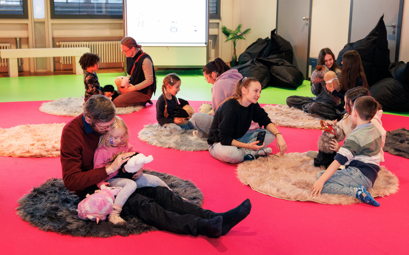 Kinder sitzen mit ihren Eltern im Elektronischen Streichelzoo