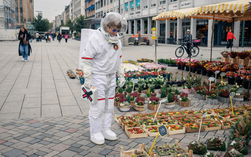 Zu sehen ist ein ZKM-Astronaut bei einem Blumenstand.
