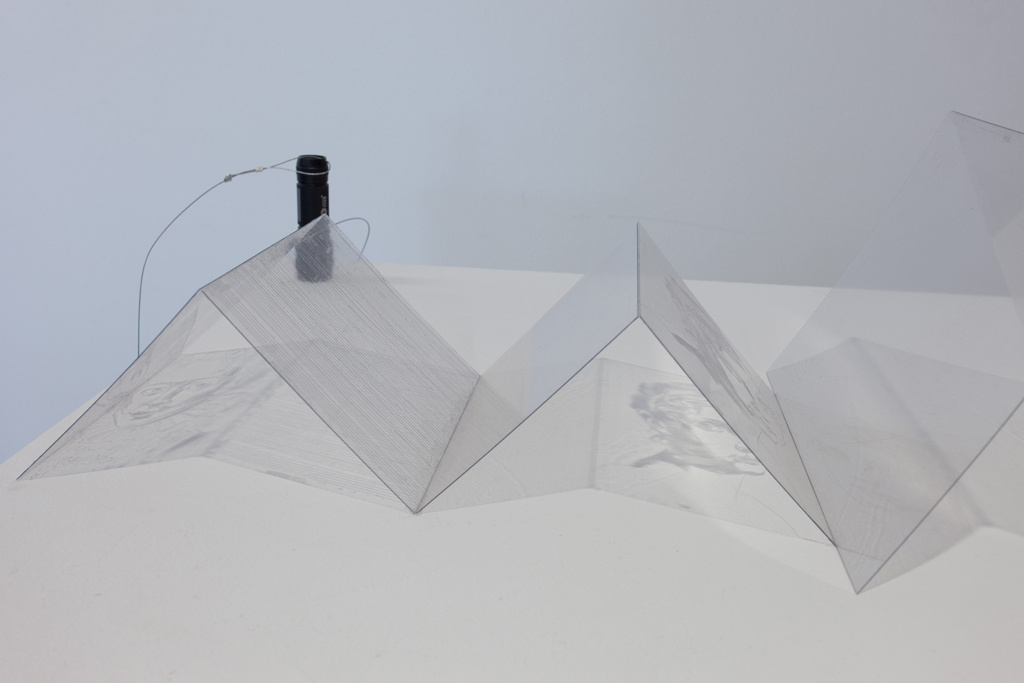Ein zu Pyramiden gefaltetes Stück Plastik, auf dem ein Gesicht zu sehen ist.