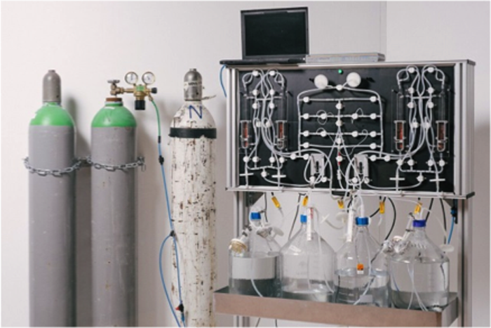 Eine Apparatur mit drei Gasflaschen links und Kolbengläsern in der Mitte