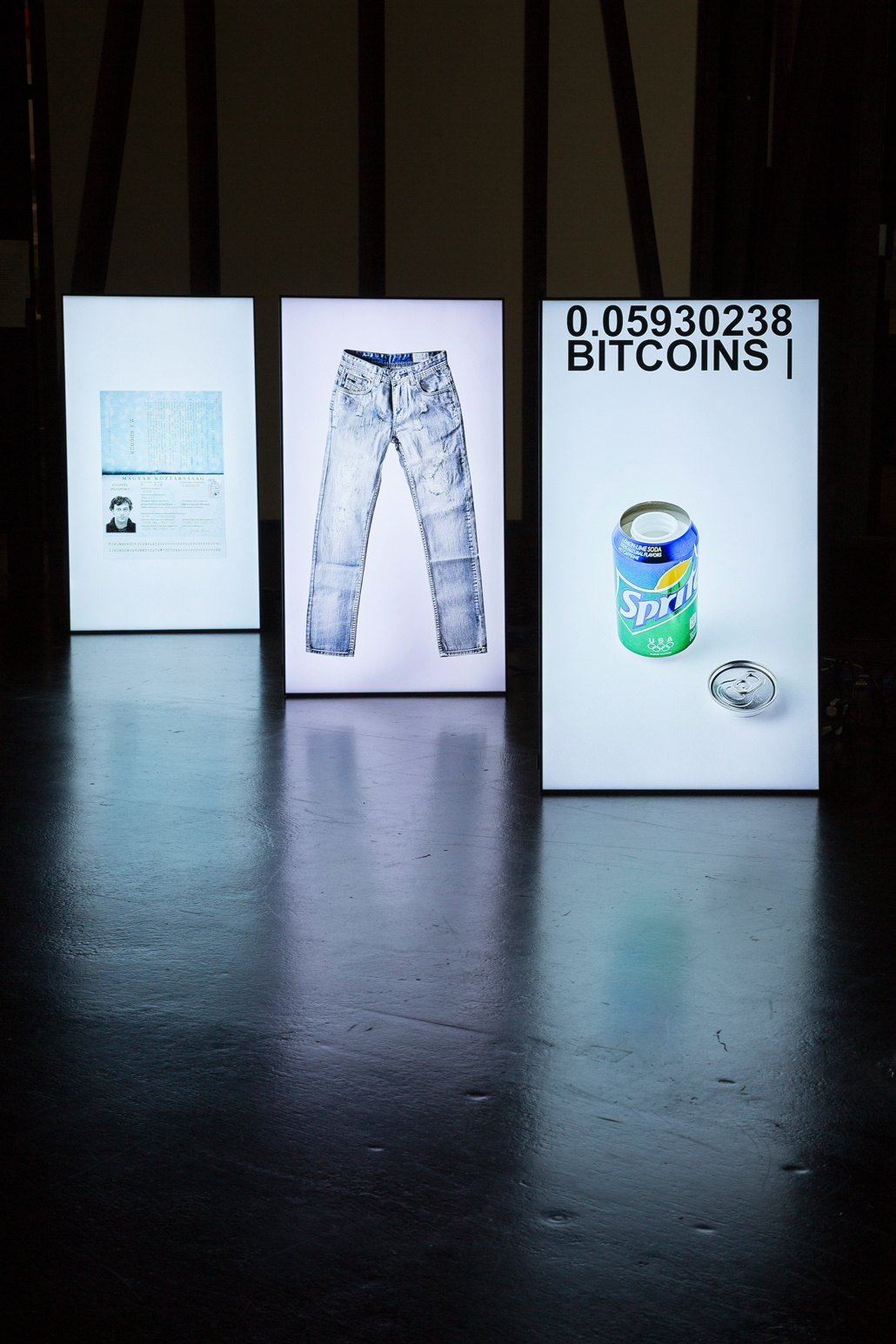 Three in a row standing luminous stands, on which a pair of pants, a sprite can and a card can be seen
