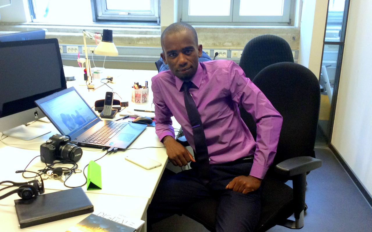 A man sits a the desk on which computers are