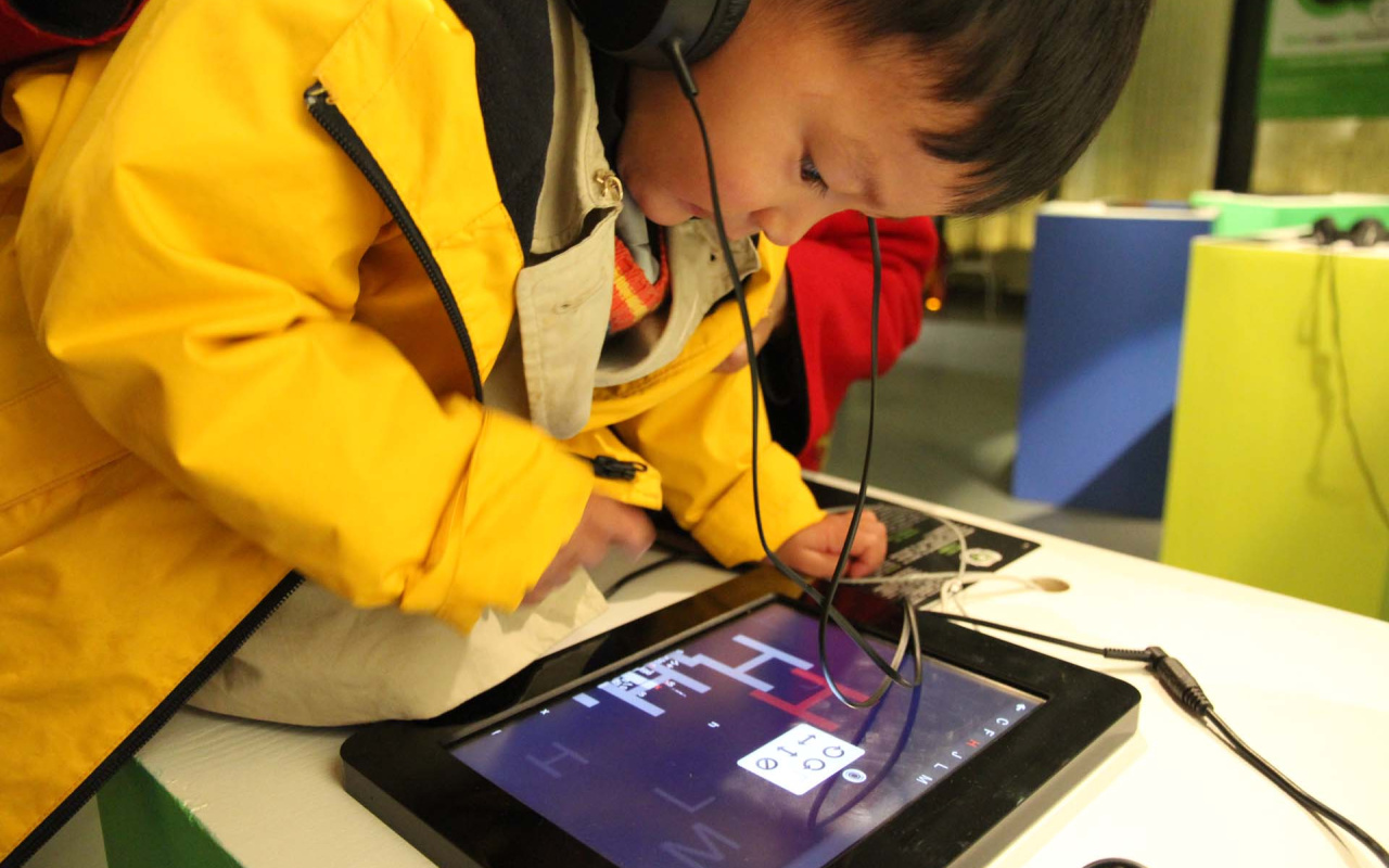 Ein kleiner chinesischer Junge ist über ein Ipad gebeugt. 