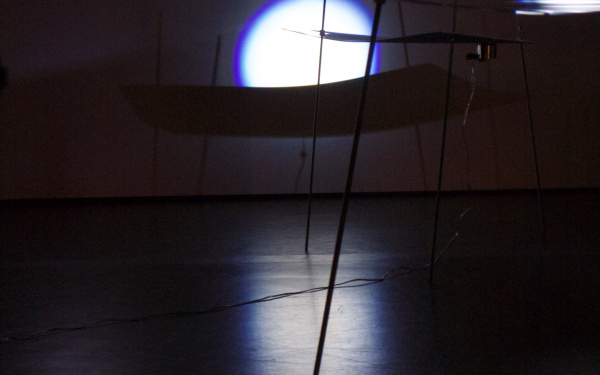 Ein dunkler Raum mit zarten Strukturen aus Plexiglas und Flüssigkeit, auf die Licht fällt.