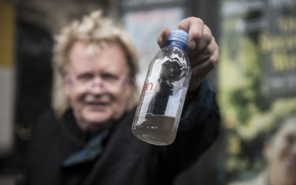 A man holding a water bottle into the camera