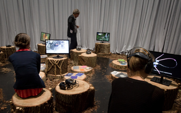 Persons sitting on tree trunks and watch videos
