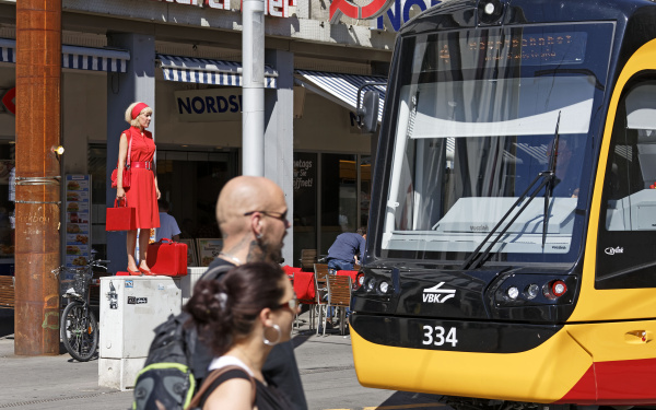 a woman in red is standing on a power box in the middle of the pedestrian zone