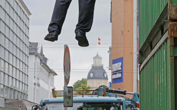A man hanging in the air, holding himself with one hand.