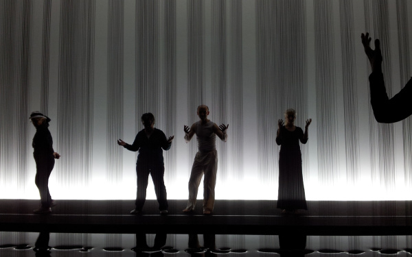 Danceworkshop in the exhibition infront of a sculpture at which streams of oil are running from the ceiling to the floor.