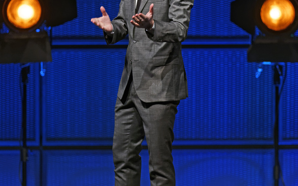 A man in a suit, standing on a stage.