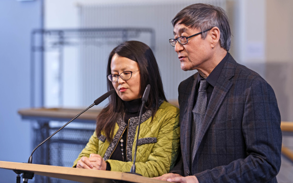 A man and a woman talking into a microphone