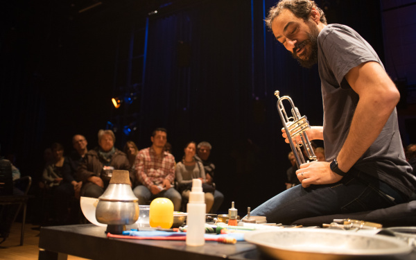 A man sits on the ground and presents different instruments