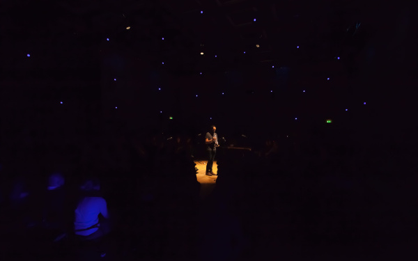 A man stands in a dark room and plays the trumpet