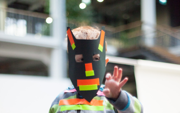 A boy with a homemade mask and various strips on clothing