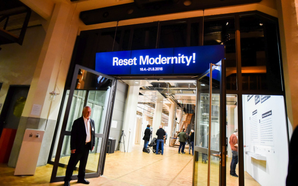 Leuchtreklame oberhalb einer Tür mit den Worten »Reset Modernity!«