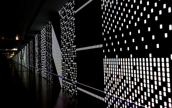 Eine schwarze Leinwand mit gepunkteten LED-Strukturen, die sich scheinbar bis Unendliche erstreckt. 