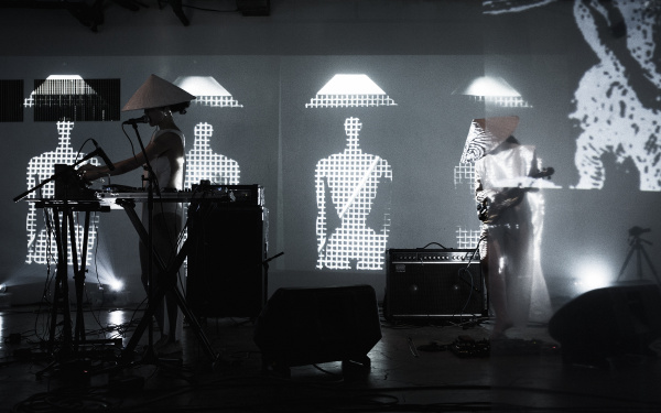 Das Duo group A performt live auf der Bühne, im Hintergrund Visuals aus abstrakten Figuren mit traditionellen asiatischen Kegelhüten