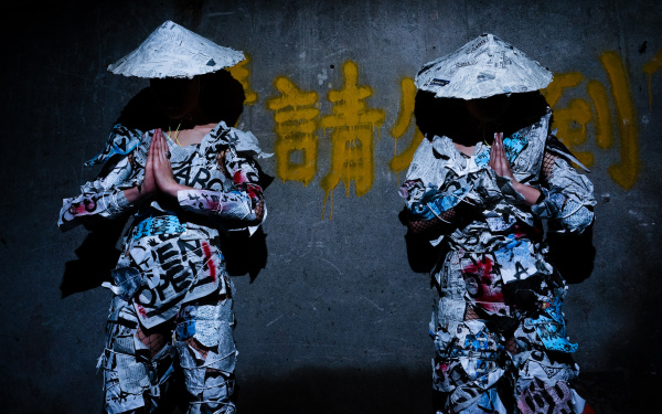Das Duo group A vor einer grauen Wand mit gelben japanischen Schriftzeichen