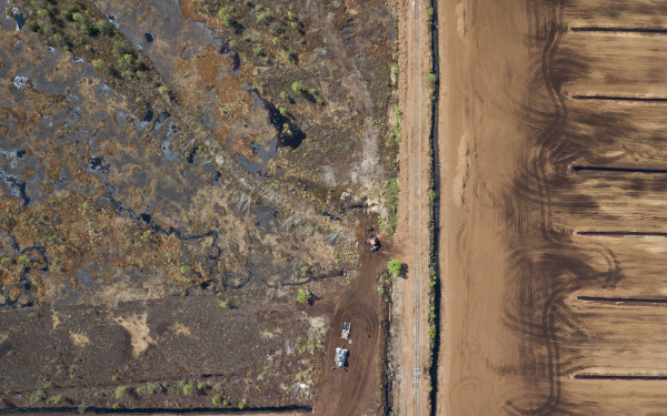 Moorlandschaft, Dronenblick von oben. Die Landschaft erscheint zweigeteilt: Links das Moor, rechts eine Fläche aus Torf, die in gleiche Teile unterteilt ist.