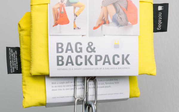Eine Kombination aus Tasche und Rucksack, faltbar, gelb, an einer Eisenkette aufgehängt