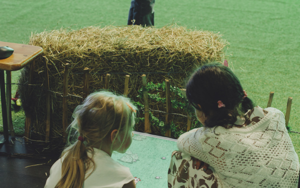 Two children sit kneeling in front of a screen