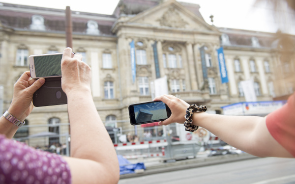 Auf Smartphone-Displays wird eine post-apokalyptische Wüste mit Mülleimern gezeigt.