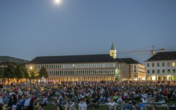 Das BIld zeigt den mit dem Publikum der Schlosslichtspiele gefüllten Vorplatz des Karlsruher Schlosses