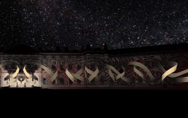The illuminated Karlsruhe Castle can be seen in front of a sky full of stars. Projected are golden ribbons intertwined with each other