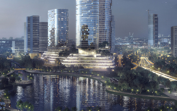Das Foto zeigt mittig ein großes modernes Hochhaus, vor anderen Hochhäusern. Davor ist Wasser, indem sich die ganzen Lichte und Gebäude spiegeln. Das Foto wurde im dunkeln aufgenomen und die ganze Stadt ist erleuchtet.