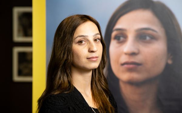 Yazidi activist Hala Safil is seen in front of the exhibition poster
