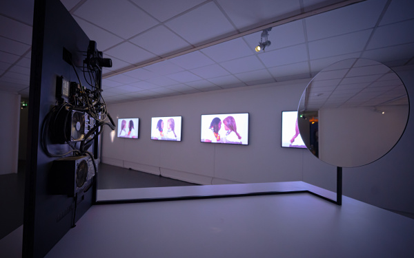  Stephanie Dinkins, »Conversations with Bina48«, 2014; Christian Mio Loclair, »Narciss«, 2018. Zu sehen ist ein runder Spiegel, der hinter einem Bildschirm befestigt ist. Im Hintergrund sind weitere Bildschirme zu sehen.
