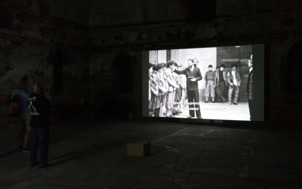 »After Pasolini – Visions of today« Zu sehe ist ein Bildschirm auf dem mehrere Personen abgebildet sind.