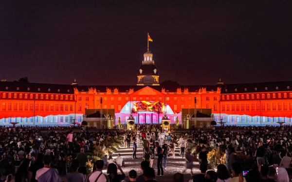 Das Schloss leuchtet rot auf. In der Mitte zu sehen ist ein Lavaerguss aus einem Vilkan. Der Himmel ist schwarz und gibt einen Kontrast zu dem hellen Schloss. Die Zuschauer werden von kleinen Strahlern auf dem Weg zum Schloss angeleuchtet.
