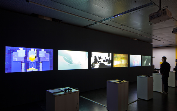 Several computer games on screen. One person playing at a game console.