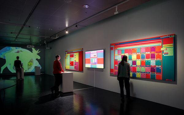 Ansicht aus der Ausstellung: Personen schauen sich Browser-Kunstwerke an den Wänden an.