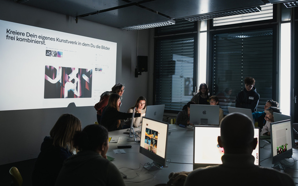 Zu sehen sind einige Personen an einem runden Tisch mit Computern.