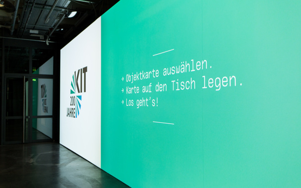 Die Bedienungsanweisung für die Ausstellung ist auf einer Bildschirmwand zu sehen.