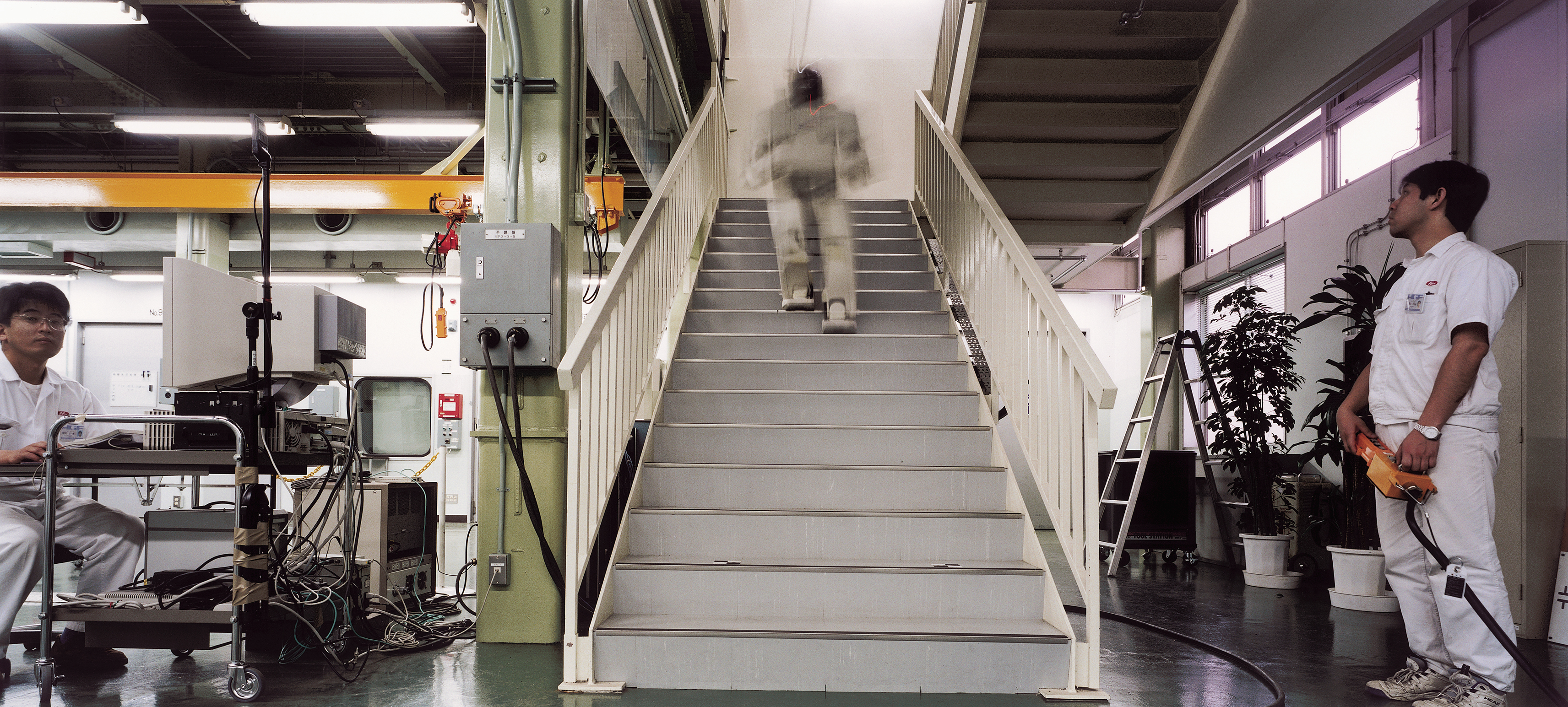 A robot walking up the stairs in an industrial building