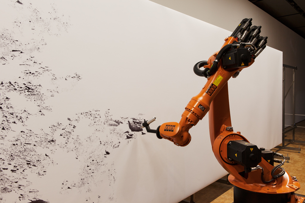 An industrial robot is drawing with pen on a large format.