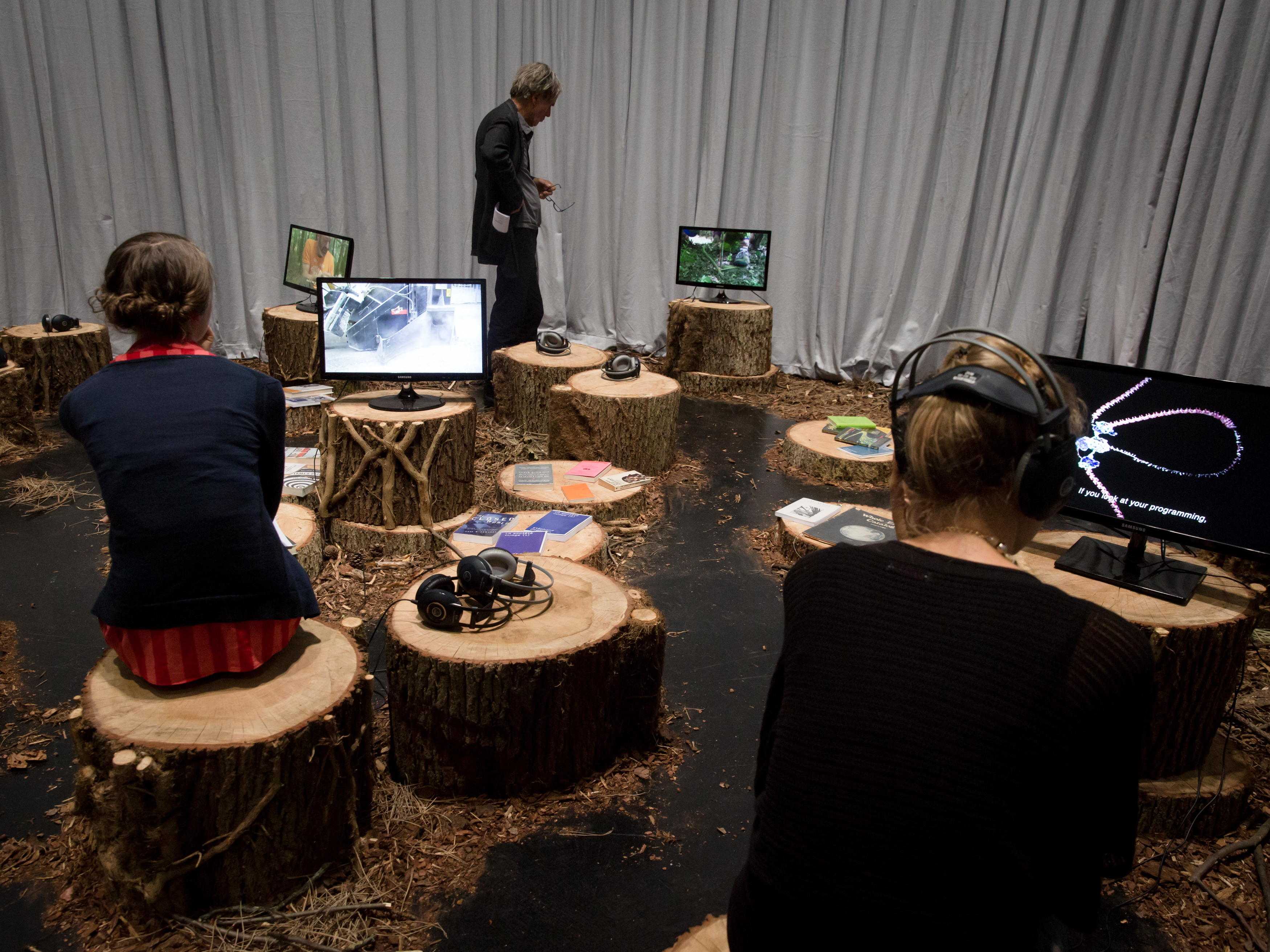 Personen sitzen auf Baumstämmen und schauen Videos