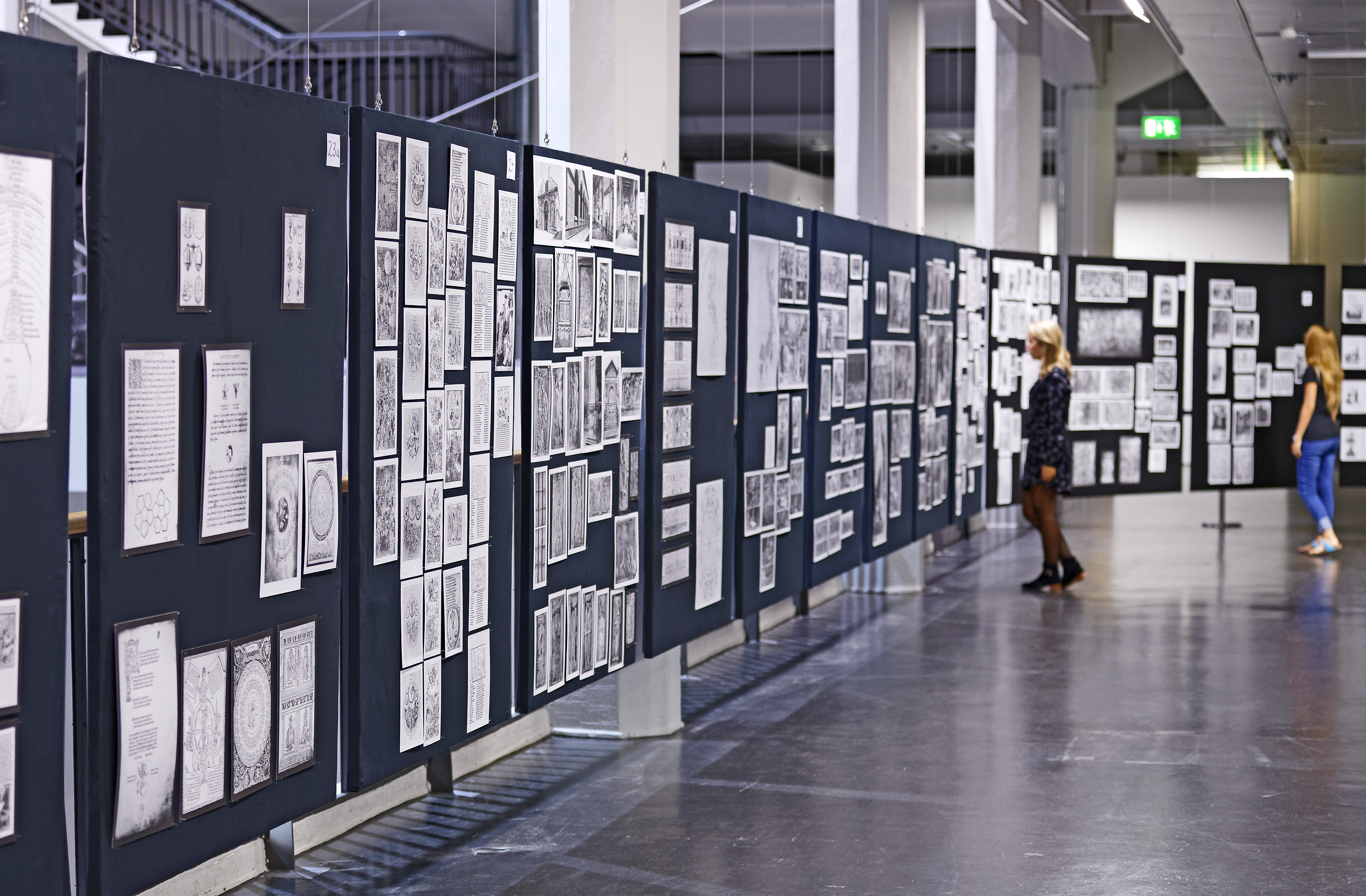 Two women are looking at the panels of Aby Warburg