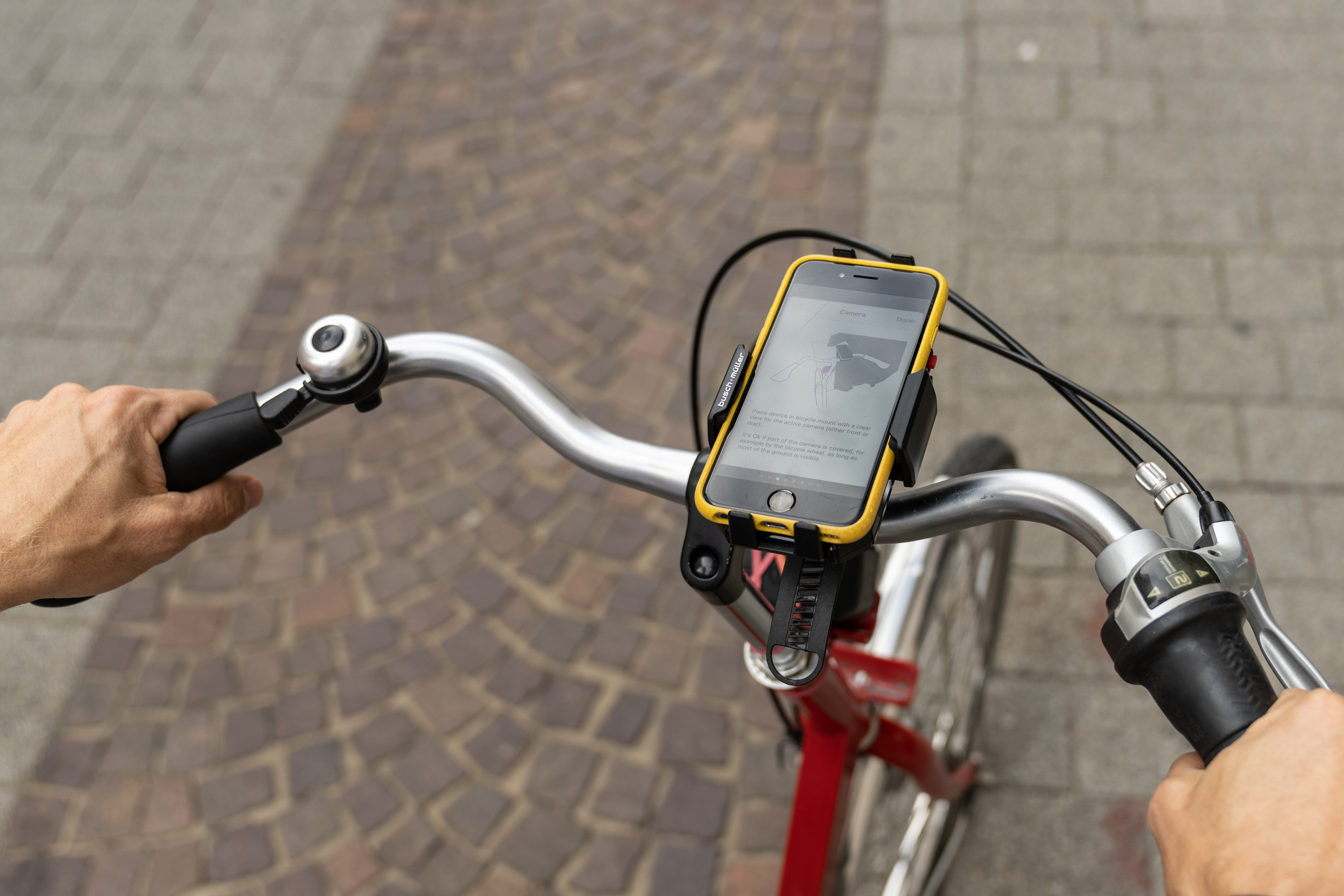 Zu sehen ist ein Ausschnitt von einem Fahrrad mit einem Handy auf der Handy-Halterung am Lenkrad.
