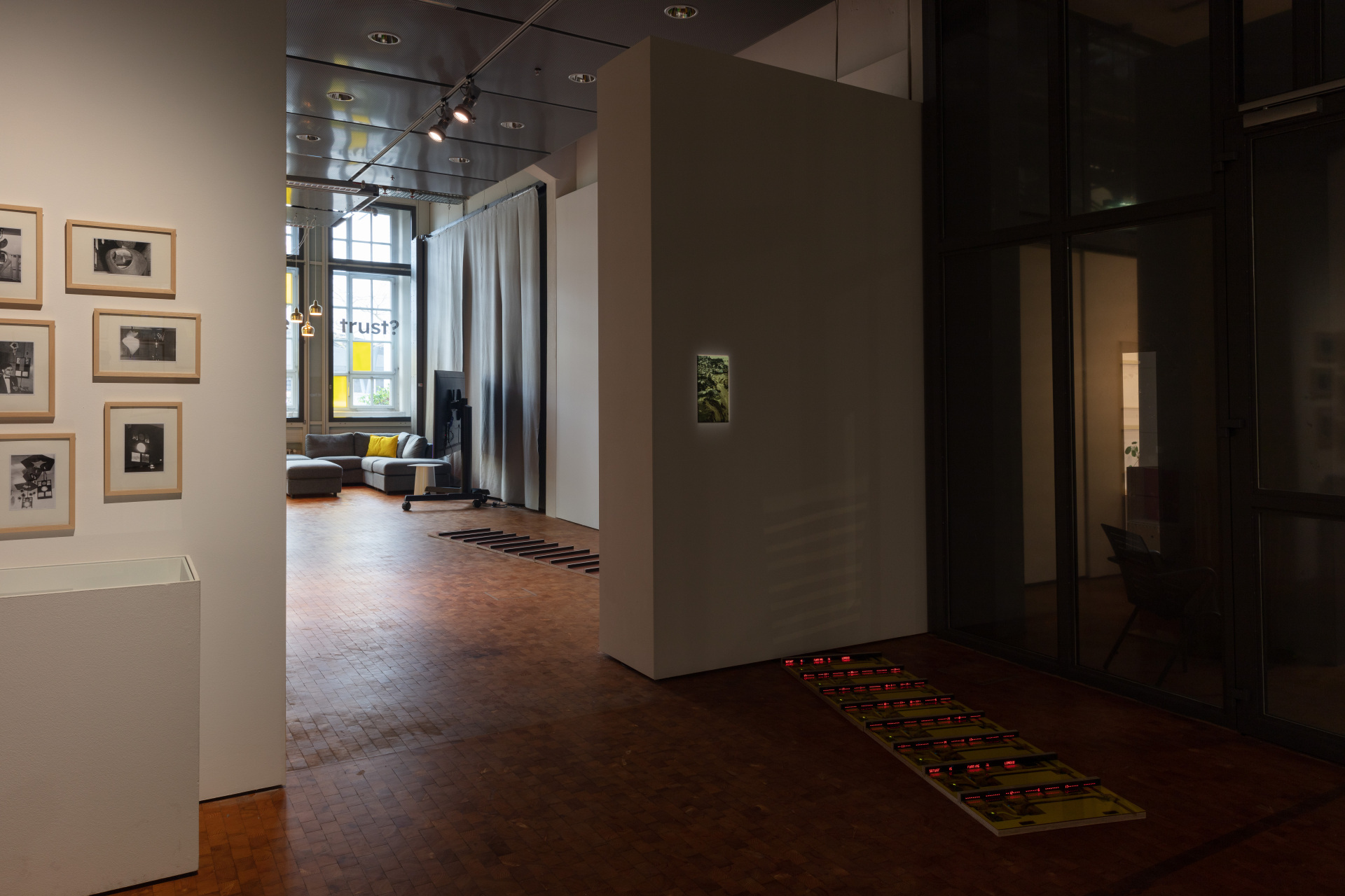 View into the exhibition of the work »Patterns of Heat« with mirrored panels placed on the floor, red glowing struts and an illuminated image of a landscape hanging on the wall