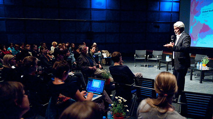 A man is giving a speach in front of a seated audience