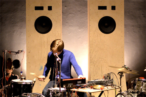 A musician in a purple shirt. He uses a mixer and plays drums.